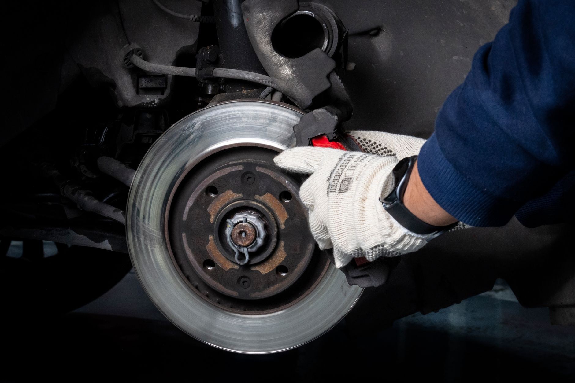 Gloved hand refitting a brake disc onto a wheel hub