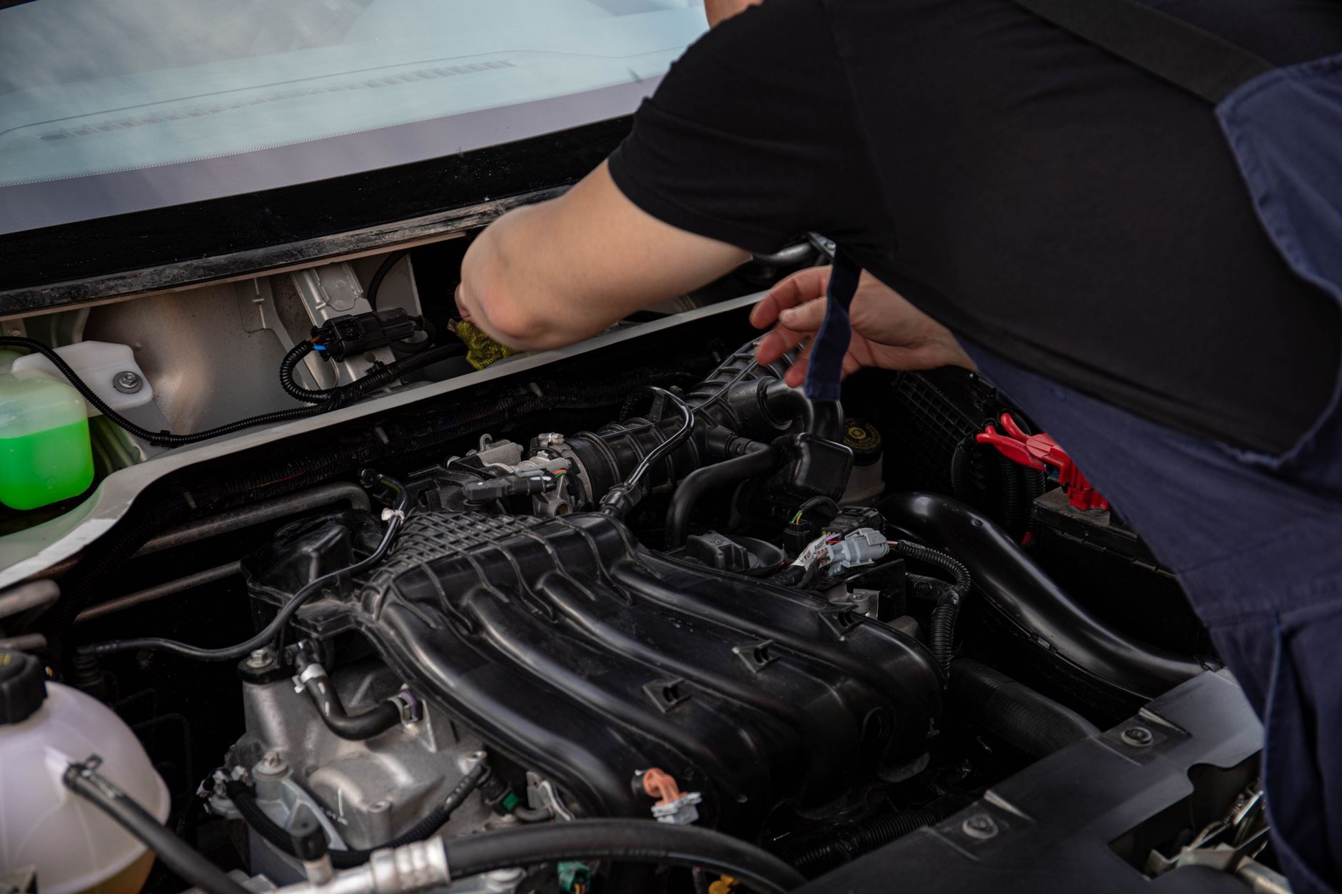 Hands using a tool deep in an engine bay during a service